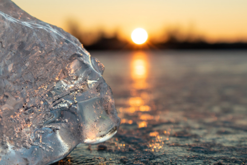 Clear ice close-up sparkling on frozen lake sunset